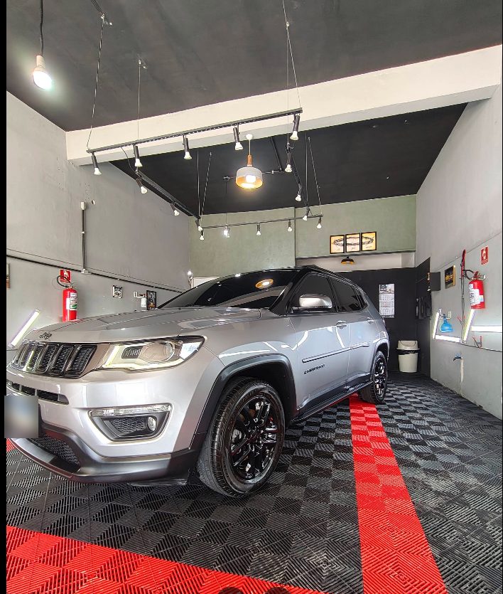 Jeep Compass prata no estúdio, com spots no teto e piso preto com faixa vermelha