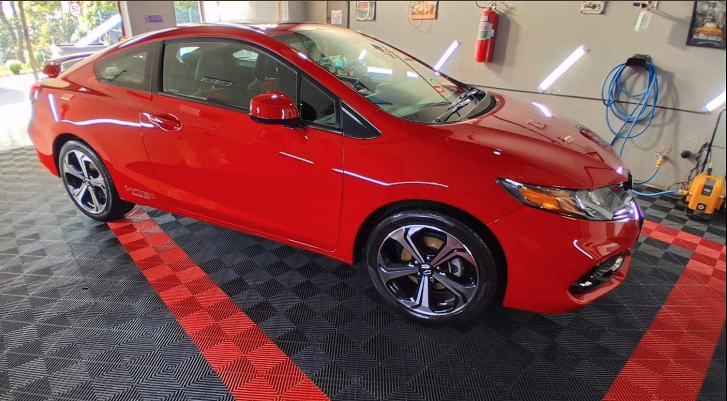 Carro vermelho com a pintura polida no estúdio da Mais Giro, sobre o piso preto com faixas vermelhas